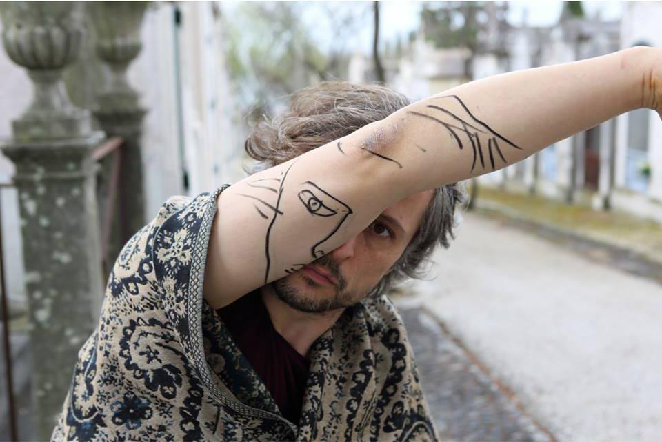 l'artista Sebastian Bieniek ritratto con un braccio sul volto a cui è stato disegnato parte del suo volto